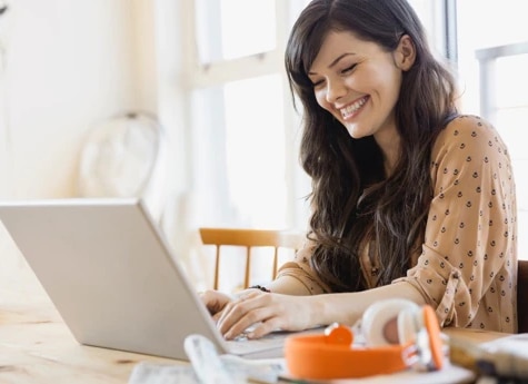 Mulher sorrindo enquanto digita no computador