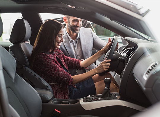 Mulher dentro de um carro com as mãos no volante.