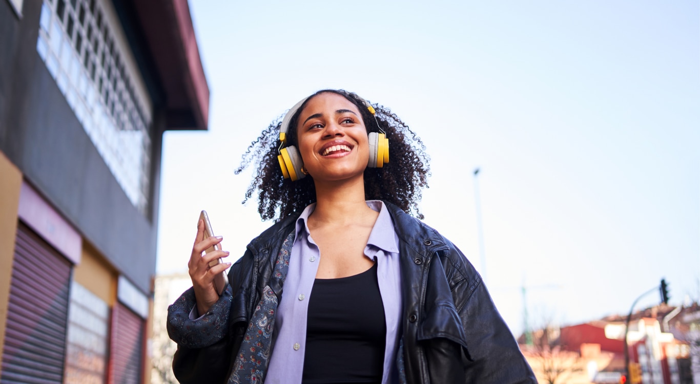 Mulher sorrindo com um fone de ouvido amarelo ouvindo música 