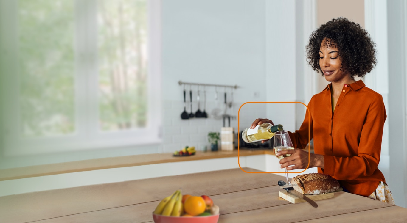 Mulher na cozinha enchendo uma taça de vinho