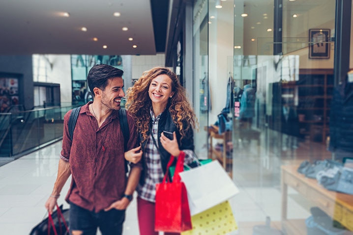 Homem e mulher passeando em um shopping representando a compra parcelada com o cartão Itaú