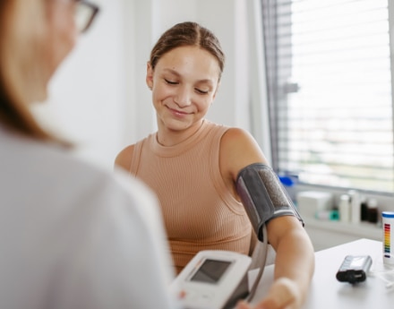 Mulher sendo atendida por um médico, com medidor de pressão