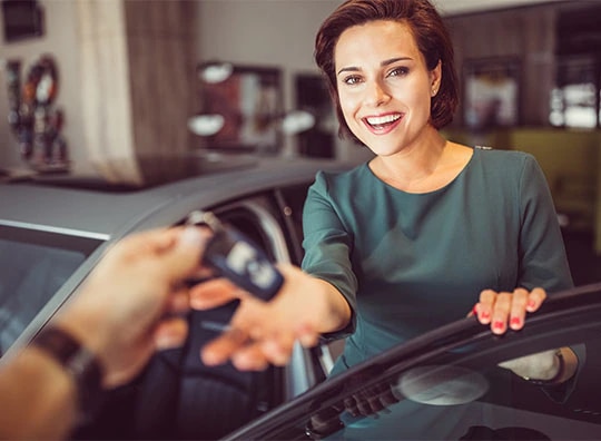 Mulher do lado de fora de um carro recebendo uma chave.