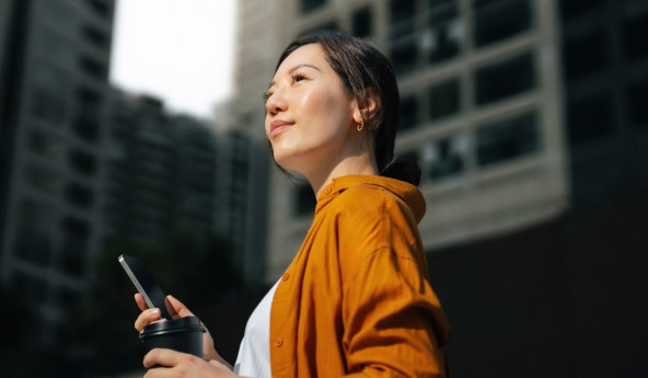 Mulher, ao ar livre, com seu celular na mão